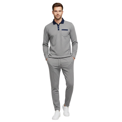 Mężczyzna ma na sobie zestaw Arkadya Outlet Komplet dresowy męski dwuczęściowy długi rękaw użytkowy z marynarskim kołnierzem, detalem kieszeni, dopasowanymi szarymi spodniami ze sznurkiem i białymi trampkami, stojąc na białym tle.