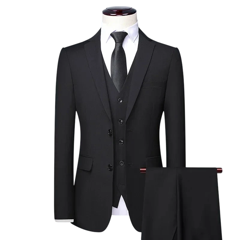 Zestaw Garniturowy Męski Trzyczęściowy Z Marynarką I Kamizelką Arkadya Outlet: czarny garnitur, biała koszula i czarny krawat na manekinie, spodnie na wieszaku, całość na jasnoszarym tle. Idealny wybór na formalne okazje.