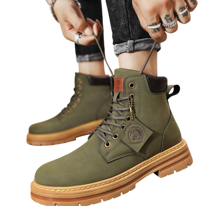 Osoba wiążąca sznurówki Arkadya Outlet Buty zimowe męskie sznurowane zamknięta forma gruba podeszwa w kolorze oliwkowym, ubrana w pierścionki i podwinięte dżinsy, na jasnym tle.