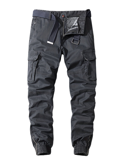 Arkadya Outlet Męskie Spodnie joggery: ciemnoszare spodnie cargo z wieloma kieszeniami, niebieskim tkanym paskiem, częściowo otwartym rozporkiem, elastycznymi mankietami przy kostkach i lekko marszczonym wykończeniem. Prezentowane na jednolitym szarym tle.