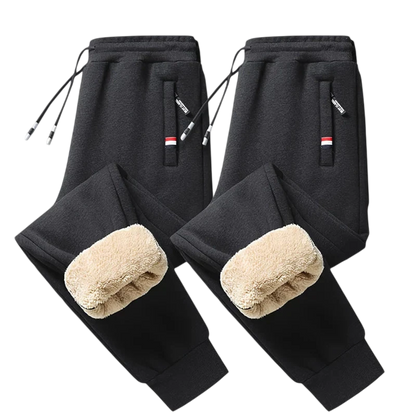 Dwie pary czarnych Arkadya Outlet Spodnie Termiczne Męskie Elastyczny Pas Z Regulacją W Talii z beżowymi puszystymi wnętrzami są pokazane na jasnoszarym tle. Każda z nich ma zapinane na zamek kieszenie w paski i sznurki ściągające - idealne na chłodne dni.