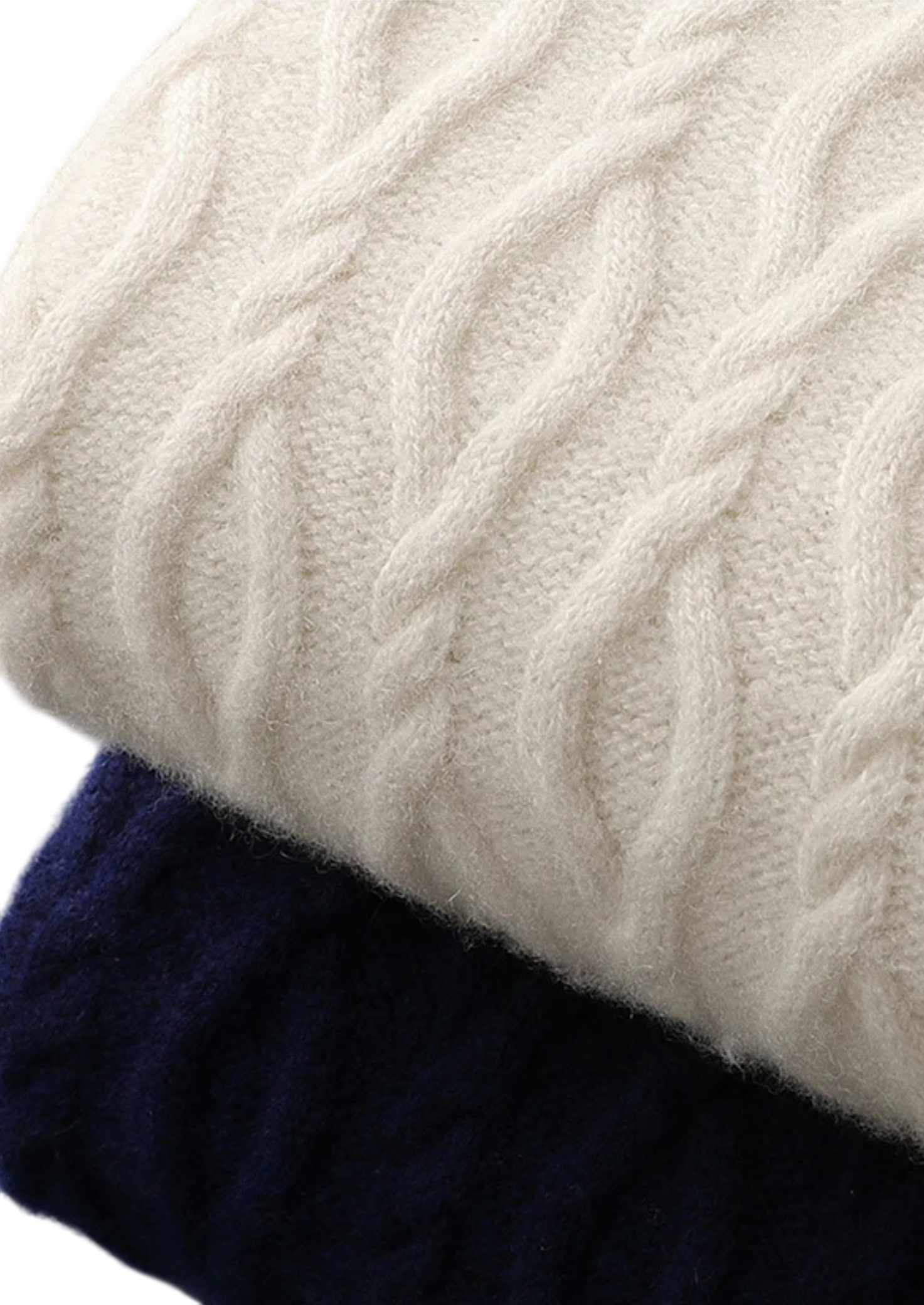 Zbliżenie na dwie złożone swetry męskie Arkadya Outlet, model "Sweter męski dekolt okrągły kontrastowa lamówka", jedna kremowa na wierzchu, druga granatowa pod spodem, podkreślające fakturowaną dzianinę i klasyczny męski styl.