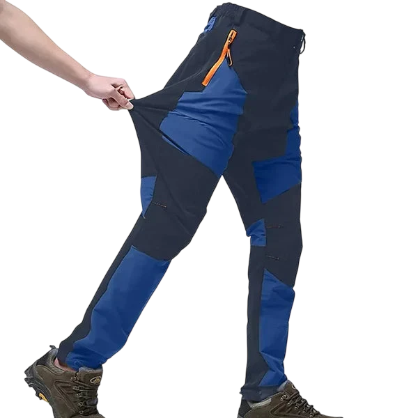Osoba w Arkadach Outlet Spodnie Terenowe Męskie Wodoodporne Wiatroszczelne Regulowane (niebiesko-czarne, pomarańczowe kieszenie na suwak) i brązowe buty turystyczne rozciągają się, aby pokazać elastyczność - idealne do aktywności na świeżym powietrzu.