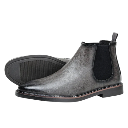 Para Arkadya Outlet Botki męskie wsuwane sztyblety zimowe w kolorze ciemnoszarym z czarnymi elastycznymi panelami, tylną zakładką i niskimi czarnymi obcasami. Jeden but stoi pionowo; drugi jest na boku, aby wyeksponować podeszwę.