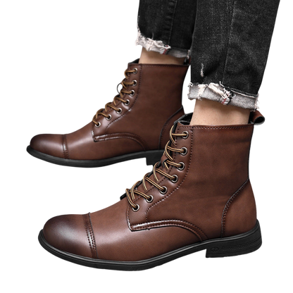 Osoba ubrana w Buty męskie wysoka cholewka z wiązaniem pełna wysokość od Arkadya Outlet, ciemnobrązowe skórzane buty z czarną podeszwą, stylizowane na postrzępione czarne dżinsy, stoi na podłodze wyłożonej kafelkami.