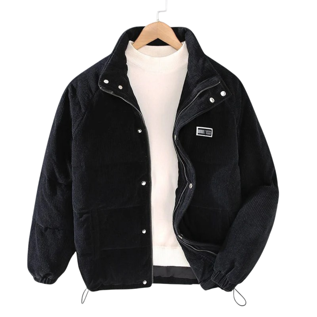 Kurtka zimowa męska strukturalny krój z czystymi liniami marki Arkadya Outlet, czarny sztruksowy puffer z guzikami zatrzaskowymi, elastycznymi mankietami i naszywką na piersi, jest prezentowany na wieszaku na białym swetrze z wysokim kołnierzem na szarym tle.