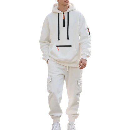 Osoba w Arkadii Outlet Męski dres wyściełane wnętrze dwuczęściowy komplet z zamkiem idzie wzdłuż parkowej ścieżki wyłożonej drzewami i kwiatami w słoneczny dzień.