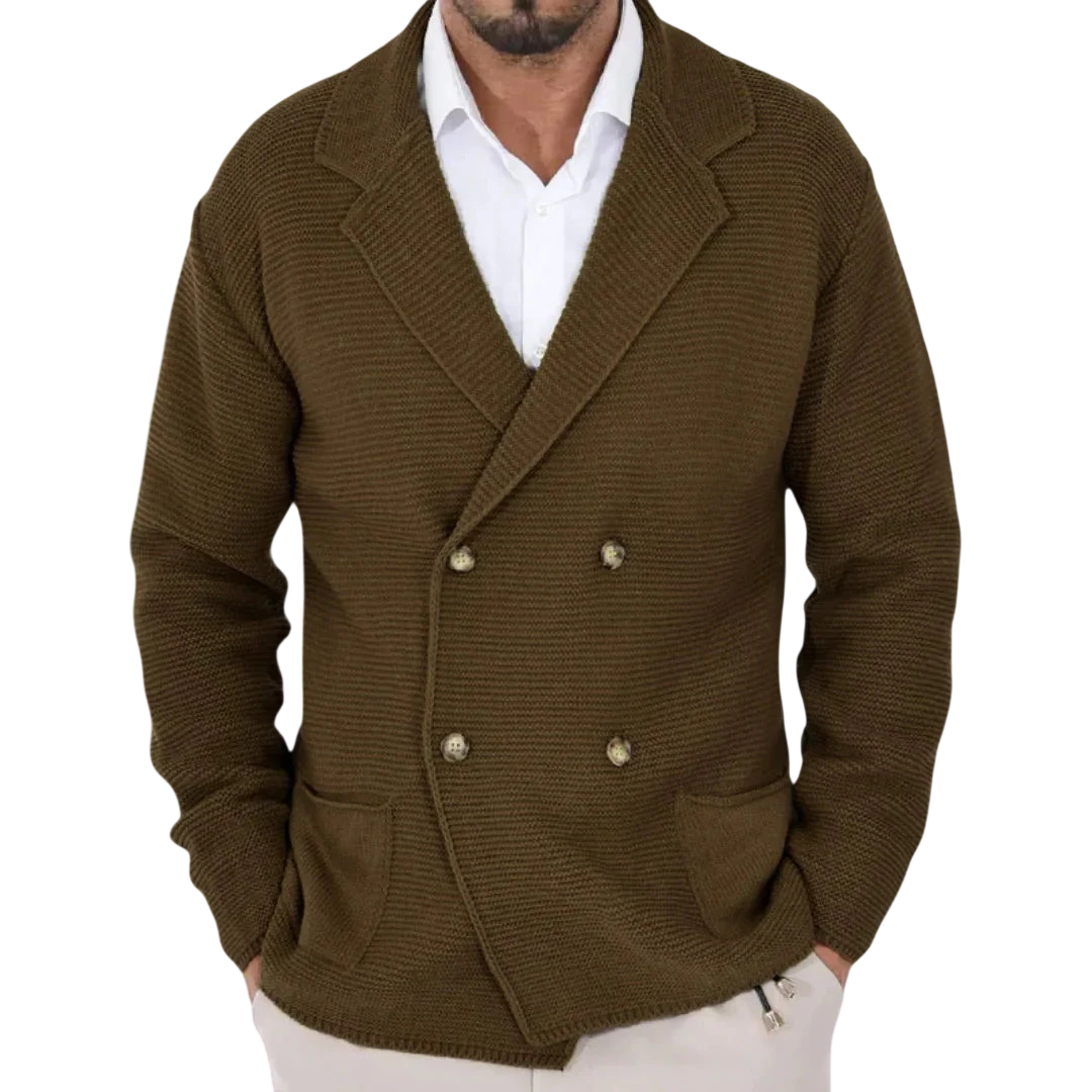 Mężczyzna nosi Męski Kardigan | Dwurzędowy Krój Typu Marynarka Z Kołnierzem marki Arkadya Outlet - brązową, dwurzędową dzianinową marynarkę z dużymi klapami - na białej koszuli, stojąc w pomieszczeniu z niewyraźnymi wieszakami na ubrania za sobą.