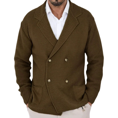 Mężczyzna nosi Męski Kardigan | Dwurzędowy Krój Typu Marynarka Z Kołnierzem marki Arkadya Outlet - brązową, dwurzędową dzianinową marynarkę z dużymi klapami - na białej koszuli, stojąc w pomieszczeniu z niewyraźnymi wieszakami na ubrania za sobą.