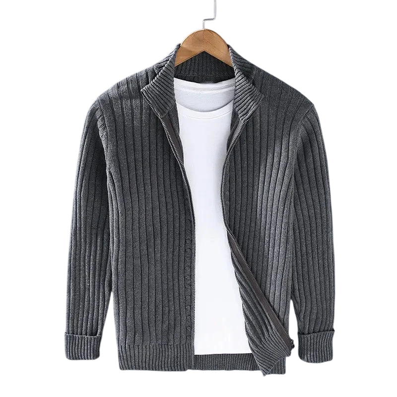 A Kardigan Męski Dzianinowy Prążkowana Faktura Zamek Długi Rękaw marki Arkadya Outlet w odcieniu szarości wisi na drewnianym wieszaku nad białym t-shirtem, na tle szarego tła.