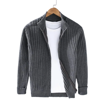 A Kardigan Męski Dzianinowy Prążkowana Faktura Zamek Długi Rękaw marki Arkadya Outlet w odcieniu szarości wisi na drewnianym wieszaku nad białym t-shirtem, na tle szarego tła.