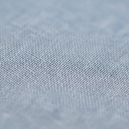 Zbliżenie jasnoniebieskiej teksturowanej tkaniny o subtelnym splocie, prezentowanej w Komplet Dwuczęściowy Męski Spodnie Robocze I Górna Część by Arkadya Outlet, podkreślającej drobne nitki i miękkie, rozmyte tło.