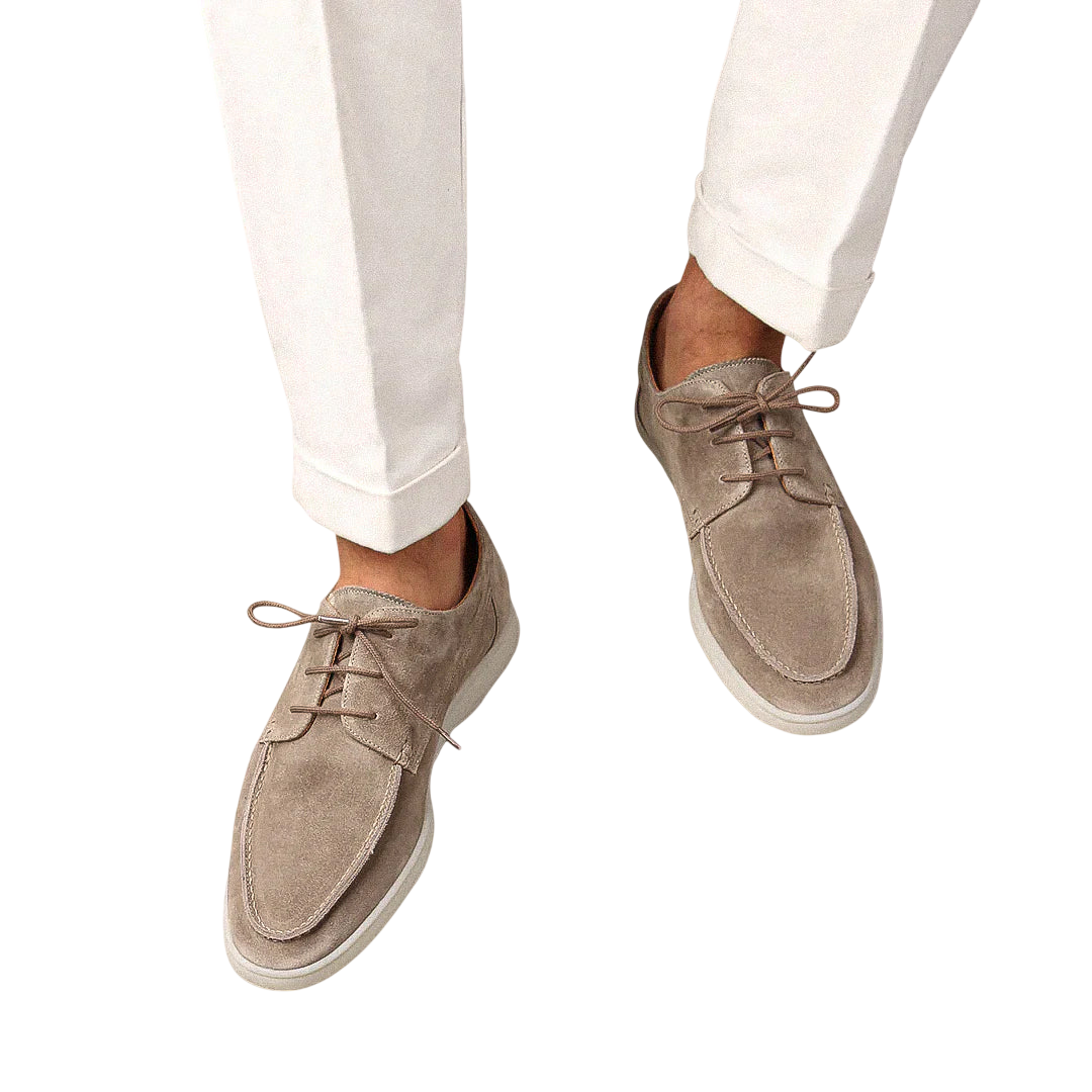 Osoba nosząca Arkadya Outlet Buty Żeglarskie Męskie Sznurowane Niskie Gumowa Podeszwa w kolorze jasnobeżowym z białymi spodniami, pokazana z góry na jednolitym jasnym tle.