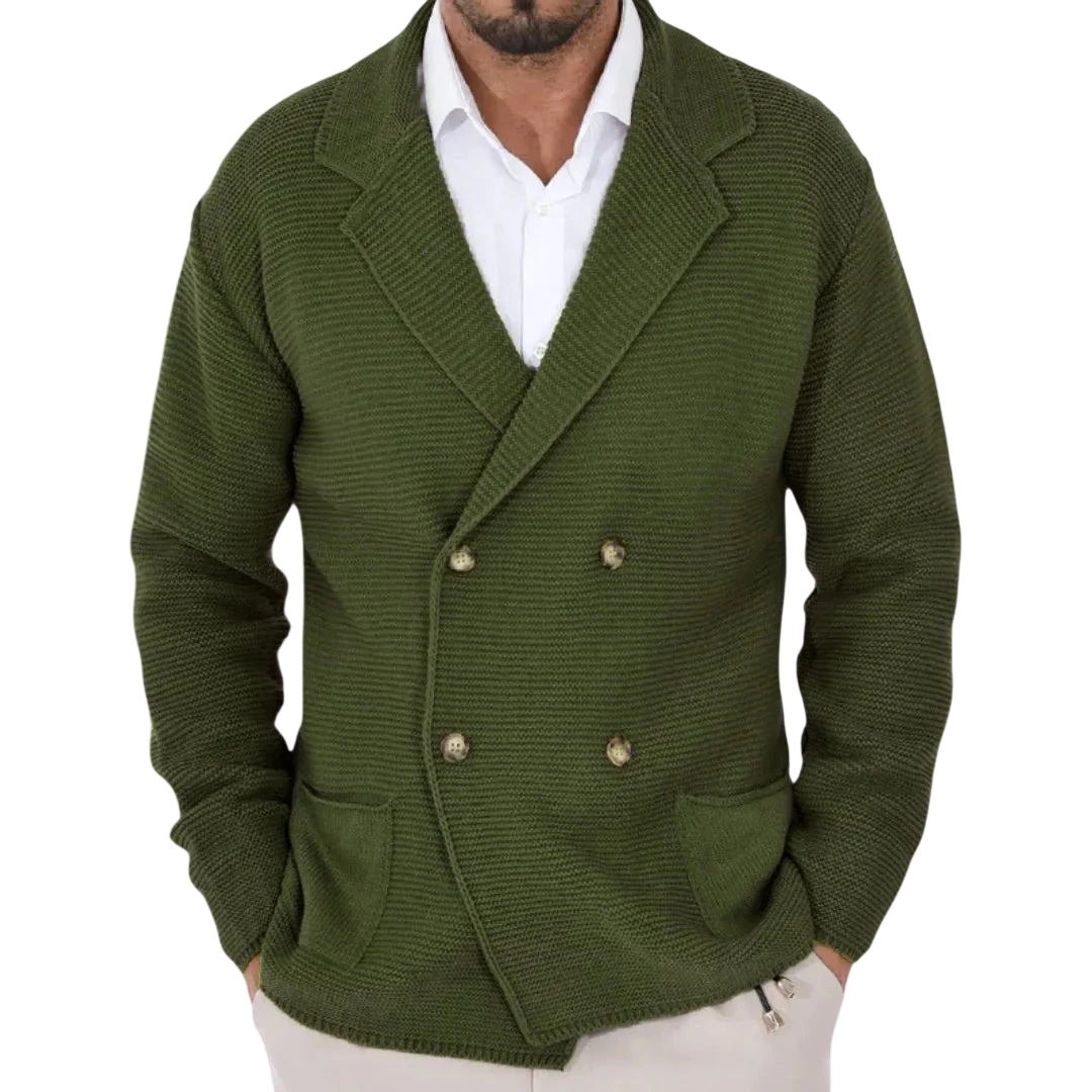 Mężczyzna w Arkadya Outlet Męski Kardigan, oliwkowozielonej dwurzędowej marynarce z kołnierzykiem, na białej koszuli i jasnych spodniach w pomieszczeniu, wieszaki na płaszcze rozmazane w tle.