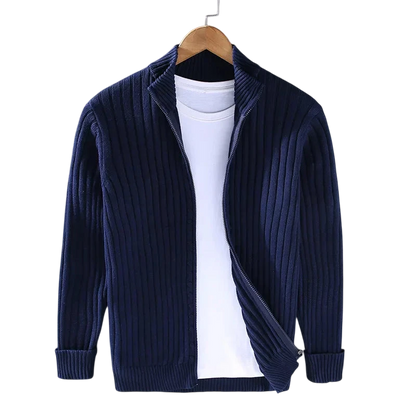 A Kardigan Męski Dzianinowy Prążkowana Faktura Zamek Długi Rękaw marki Arkadya Outlet w kolorze granatowym wisi na drewnianym wieszaku na białym t-shircie, częściowo rozpięty, na tle szarej ściany.