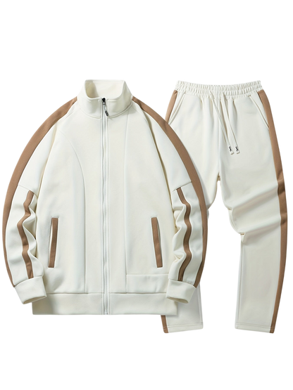 Komplet dresowy męski dwuczęściowy codzienny strój marki Arkadya Outlet w kolorze kremowym z brązowymi paskami, wyposażony w zapinaną na zamek kurtkę z dwiema kieszeniami z przodu oraz dopasowane spodnie z elastycznym paskiem w talii i sznurkiem do ściągania.