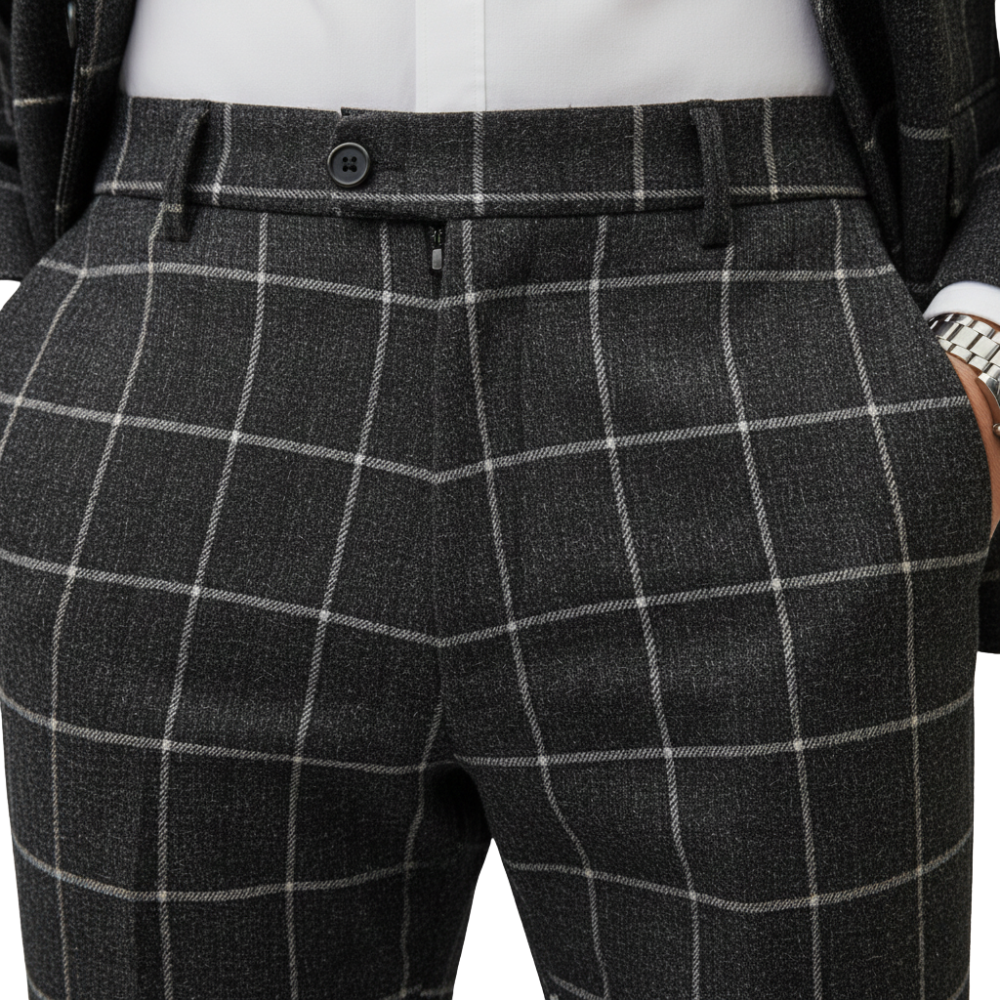 Zbliżenie na osobę ubraną w kurtkę Arkadya Outlet Komplet Garniturowy Męski Trzyczęściowy Marynarka w szarą kratę z białymi liniami windowpane, w stylizacji z białą koszulą i srebrnym zegarkiem, ręce w kieszeniach.