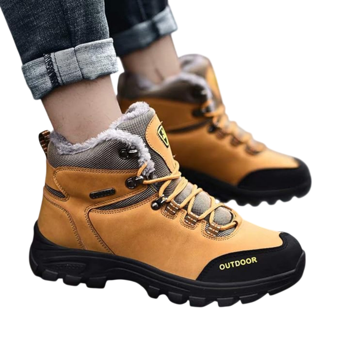 Osoba w podwiniętych dżinsach i Arkadya Outlet Buty zimowe outdoor męskie wiązane z antypoślizgową podeszwą, z futrzaną podszewką i metalowymi oczkami z napisem "OUTDOOR" z boku - idealne na zimowe przygody.