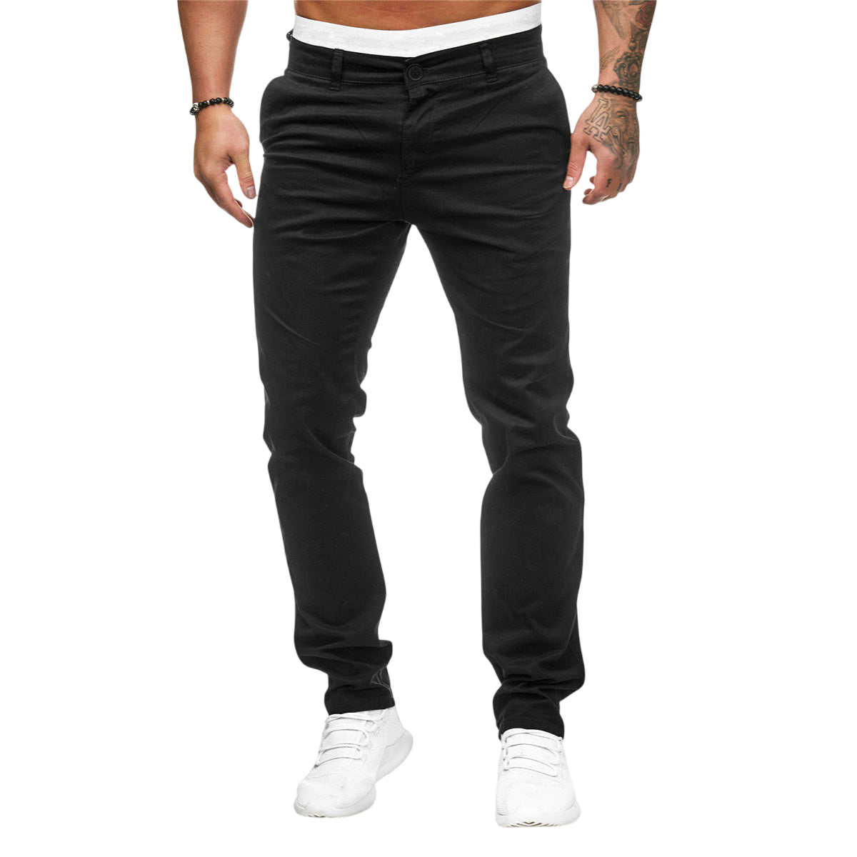 Mężczyzna ma na sobie Arkadya Outlet Męskie spodnie | Dopasowany krój prosta nogawka, białą koszulę, białe trampki, bransoletki i ujawnia tatuaże na lewym ramieniu, stojąc na prostym jasnoszarym tle.