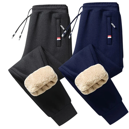 Dwie pary Arkadya Outlet Spodnie Termiczne Męskie Elastyczny Pas Z Regulacją W Talii - jedna czarna, druga granatowa - z kieszeniami zapinanymi na zamek i kostkami wyściełanymi polarem, idealne na chłodne dni, prezentowane na jasnoszarym tle.