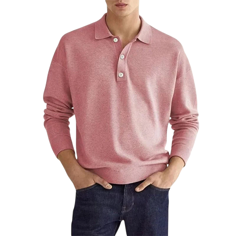 Mężczyzna w koszulce Arkadya Outlet Koszulka polo męska długi rękaw półguziki kołnierz design, jasnoróżowy z białymi guzikami i ciemnoniebieskie dżinsy stoi ręce w kieszeniach na jednolitym białym tle.