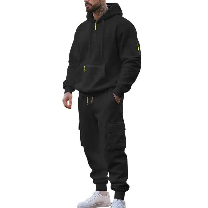 Mężczyzna nosi Arkadya Outlet Męski dres wyściełane wnętrze dwuczęściowy komplet z zamkiem z żółtymi akcentami, stojąc na parkowej ścieżce we wczesnym porannym słońcu, otoczony drzewami i trawą.