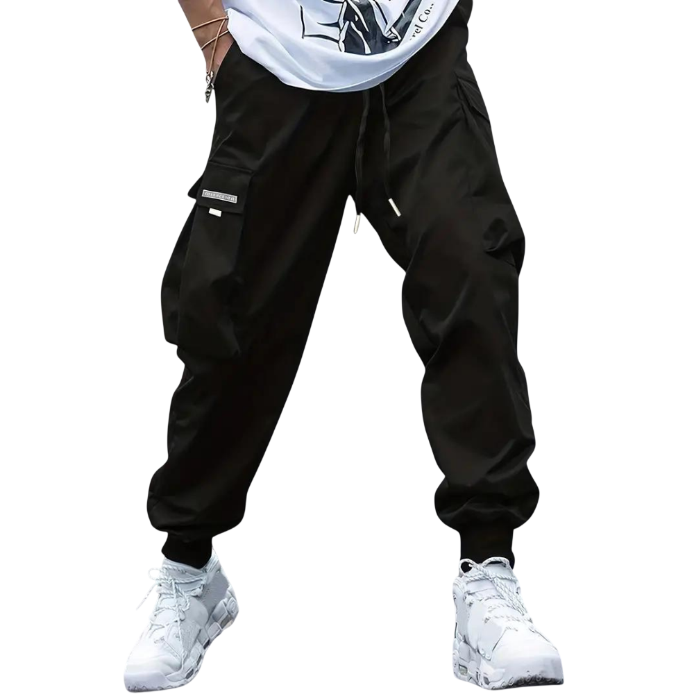 Model noszący Arkadya Outlet Męskie spodnie cargo z dopasowaną nogawką i wieloma kieszeniami, czarne, zestawione z białymi sneakersami. Widoczna tylko dolna część sylwetki na jasnoszarym tle.