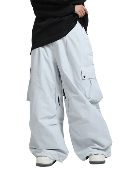 Osoba ubrana w ponadgabarytowe Arkadya Outlet Spodnie zimowe męskie szeroki krój regularny, z dużymi kieszeniami cargo, luźną czarną koszulą i białymi trampkami na jasnoszarym tle. Te zimowe spodnie są idealne na zimę i dotykają ziemi.