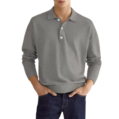 Mężczyzna ma na sobie koszulkę polo Arkadya Outlet Koszulka męska długi rękaw półguziki kołnierz wzór w kolorze jasnoszarym z białymi guzikami i klasycznym kołnierzykiem, w połączeniu z ciemnoniebieskimi dżinsami, stojąc z rękami w kieszeniach na białym tle.