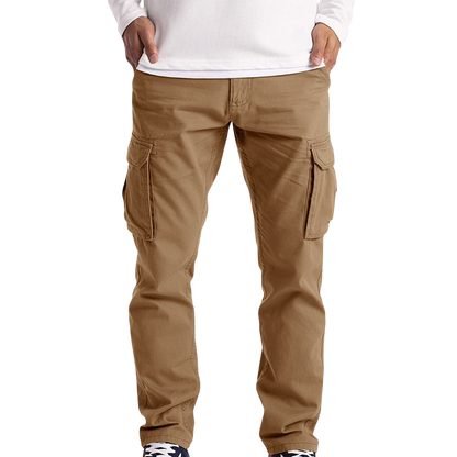 Mężczyzna w Spodnie cargo męskie luźny krój z kieszeniami na dzień codzienny Arkadya Outlet, białej koszuli z długim rękawem i czarno-białych sneakersach stoi na prostym tle - idealny do noszenia na co dzień.