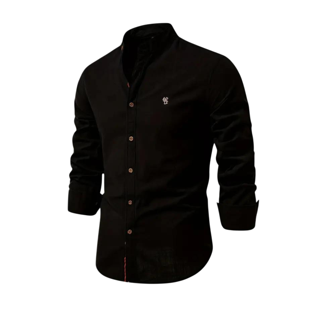 Koszula męska Arkadya Outlet z kołnierzem stójka, w czerni, długi rękaw, krój regularny, małe białe logo na lewej piersi. Idealna do codziennego użytku. Prezentowana na tle jasnego, rozmytego wnętrza.