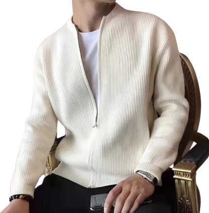 Osoba siedzi na krześle, trzyma smartfon i ma na sobie Arkadya Outlet Męski kardigan | Zapinany Na Zamek Błyskawiczny Dopasowany Krój na białej koszulce. Ich głowa jest lekko odwrócona, nie w pełni widoczna.