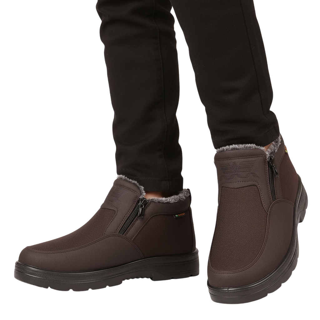 Osoba w czarnych spodniach i Arkadya Outlet Męskie buty wodoodporne antypoślizgowe zimowe obuwie z zamkami błyskawicznymi i podszewką ze sztucznego futra stoi na białym tle. Te brązowe buty mają wytrzymałą, antypoślizgową podeszwę na zimne dni.