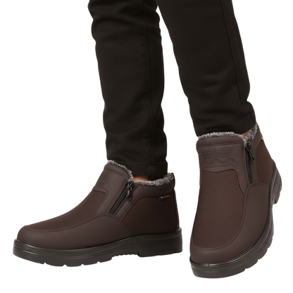 Osoba w czarnych spodniach i Arkadya Outlet Męskie buty wodoodporne antypoślizgowe zimowe obuwie z zamkami błyskawicznymi i podszewką ze sztucznego futra stoi na białym tle. Te brązowe buty mają wytrzymałą, antypoślizgową podeszwę na zimne dni.