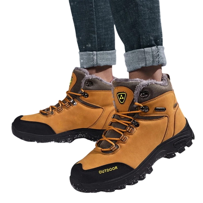 Mężczyzna nosi Buty zimowe outdoor męskie wiązane z antypoślizgową podeszwą Arkadya Outlet w kolorze brązowym i czarnym, z futrzaną podszewką, chropowatą podeszwą, bocznym logo; stylowo łączą się z podwiniętymi dżinsami powyżej kostek.