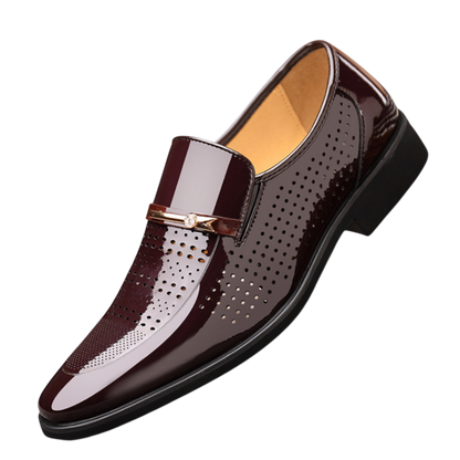 Arkadya Outlet Mokasyny Wizytowe Męskie Wsuwany Szpiczasty Nosek to błyszczące ciemnobrązowe wsuwane buty męskie z perforowanymi detalami, złotym akcentem z przodu i niskim czarnym obcasem, pokazane na białym tle.