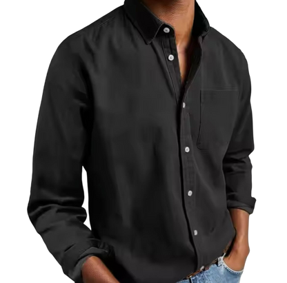 Osoba w Arkadya Outlet Koszula męska klasyczny krój proste linie regularna długość z długimi rękawami i przednią kieszenią, ręce w kieszeniach jasnoniebieskich dżinsów, stoi na jednolitym jasnym tle.