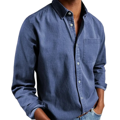 Osoba nosząca Arkadya Outlet Koszula męska klasyczny krój proste linie regularna długość, z długimi rękawami i przednią kieszenią, łączy ją z jasnoniebieskimi dżinsami i stoi z rękami w kieszeniach na jednolitym tle.