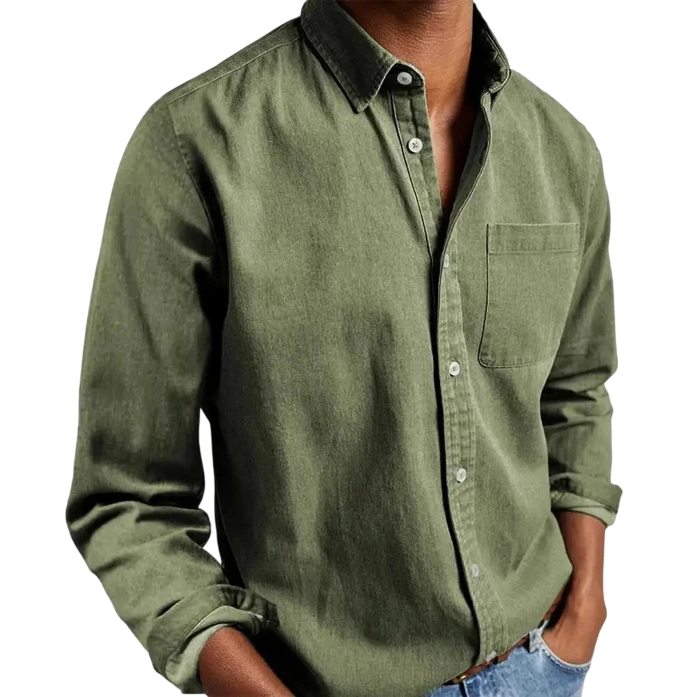 Osoba modeluje Arkadya Outlet Koszula męska klasyczny krój prosta linia regularna długość w kolorze oliwkowym, podwinięte rękawy, w połączeniu z jasnoniebieskimi dżinsami i rękami w kieszeniach - elegancki styl koszuli do pracy.